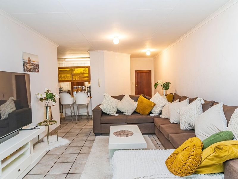 Open plan living area featuring ceramic tiled flooring, coved ceilings, and a breakfast bar connecting to the kitchen space.