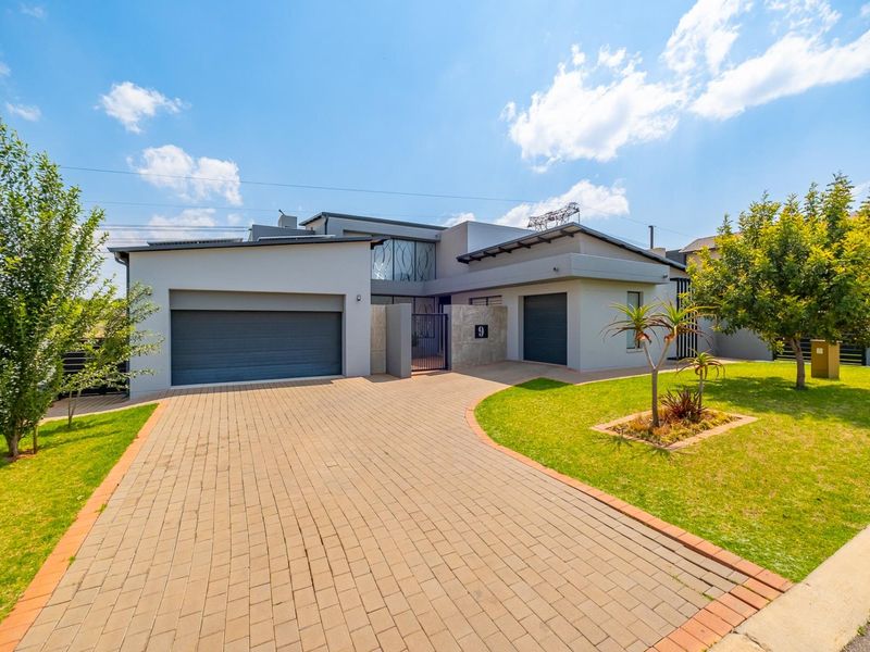 Modern contemporary house exterior featuring a paved driveway, double and single garages, and a well-maintained front garden.