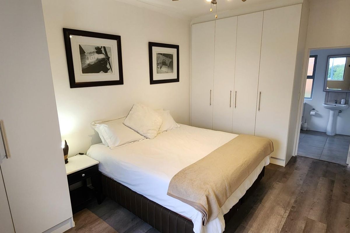 A well-maintained bedroom featuring built-in wardrobes, modern laminate flooring, and direct access to an en-suite bathroom.