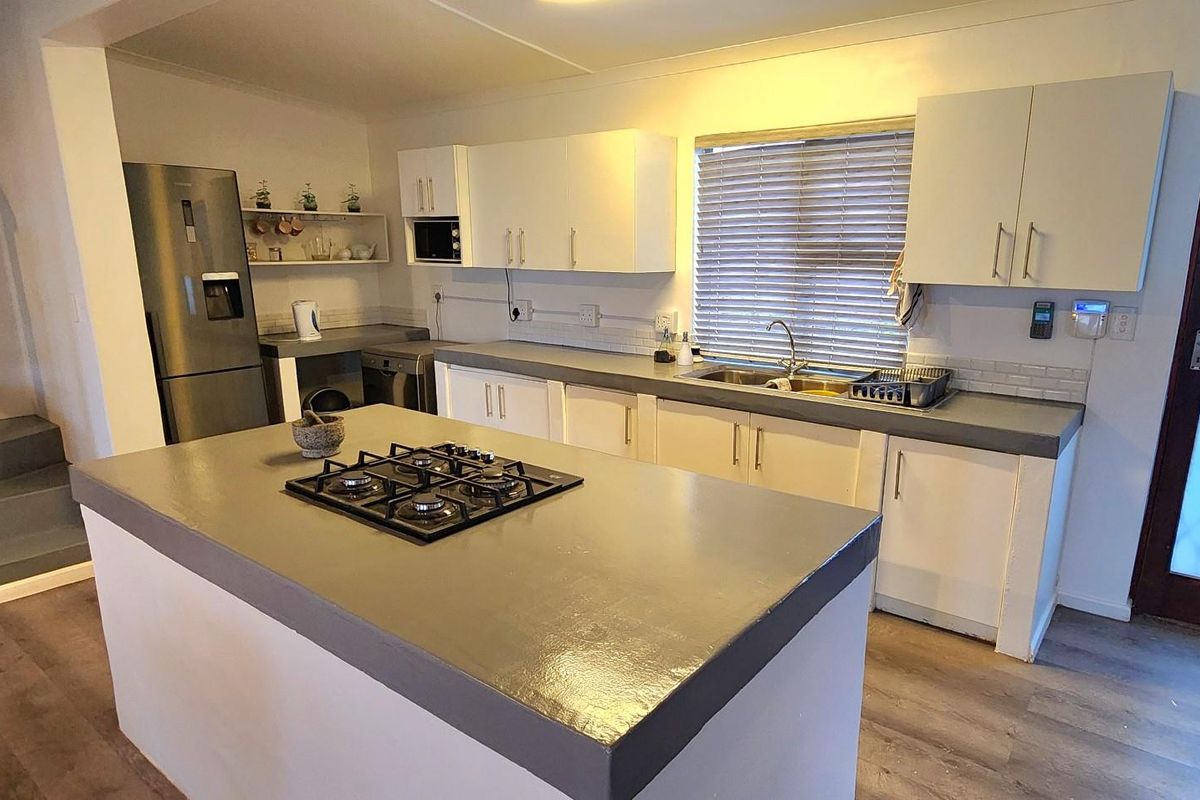 A functional kitchen featuring a central island with a gas hob, ample cabinetry, and laminate flooring, providing a practical workspace for cooking and preparation.