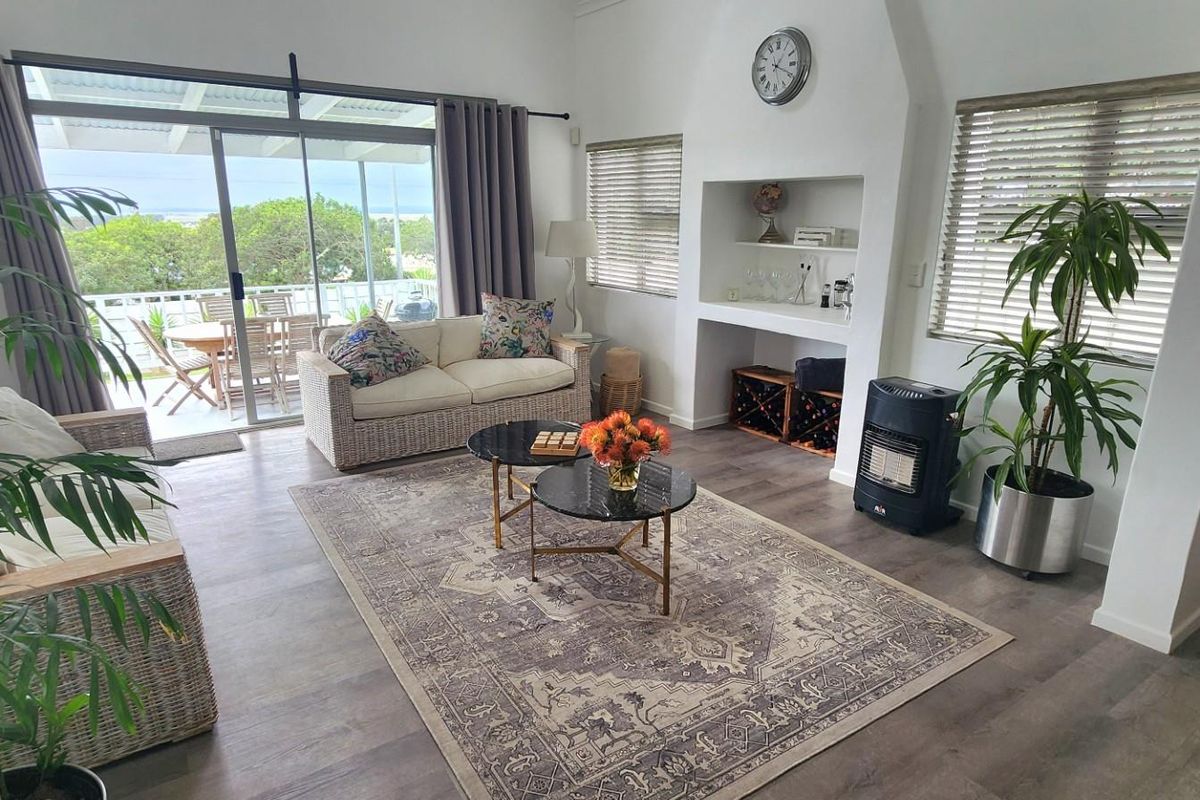 A bright living room featuring laminate flooring, built-in shelving, and large sliding glass doors that open onto an outdoor patio area.
