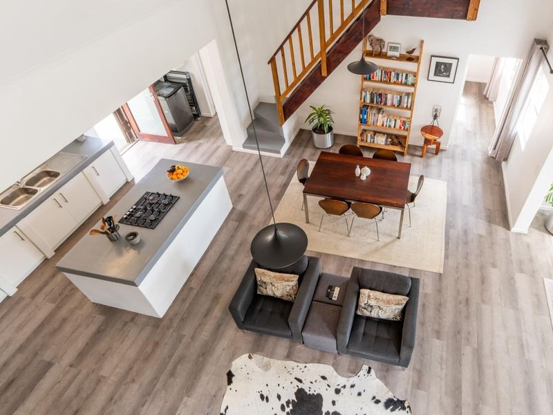 Spacious open-plan living area featuring a modern kitchen with island, gas cooktop, and timber staircase leading to an upper level.