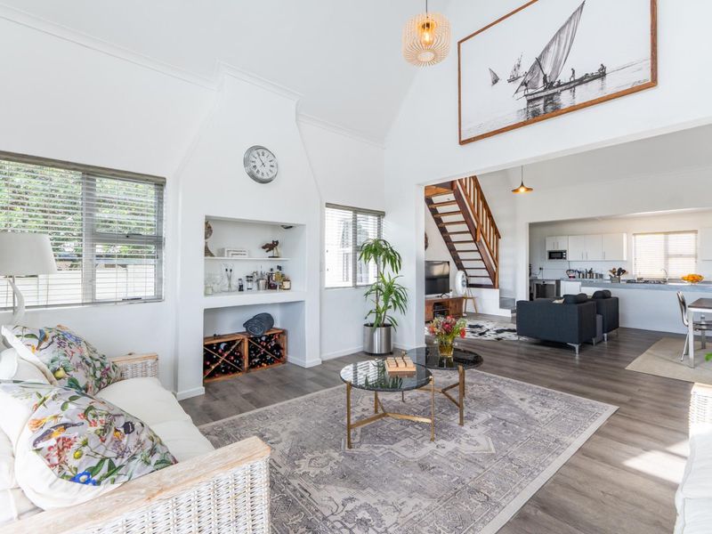 Spacious open-plan living area featuring a vaulted ceiling, built-in fireplace alcove, and a timber staircase leading to the upper level.