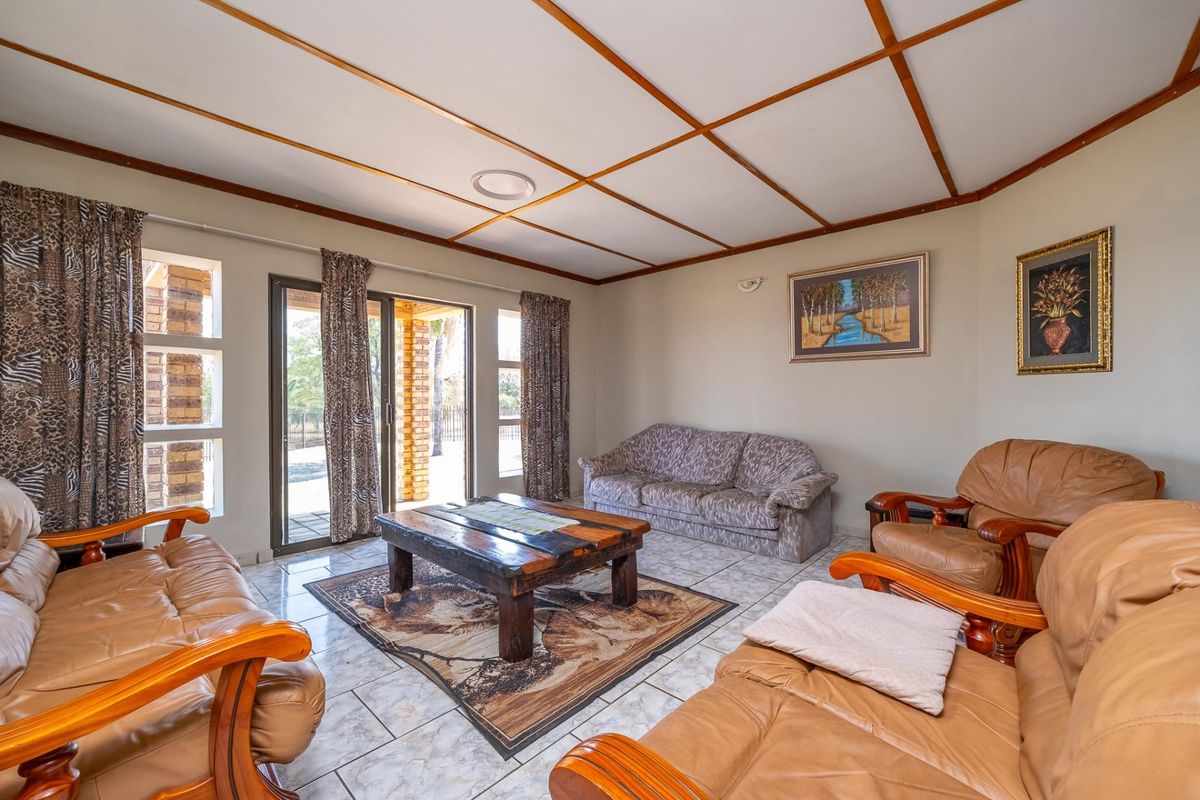A living room featuring tiled flooring, a grid ceiling, and a sliding glass door providing access to the outdoor area.