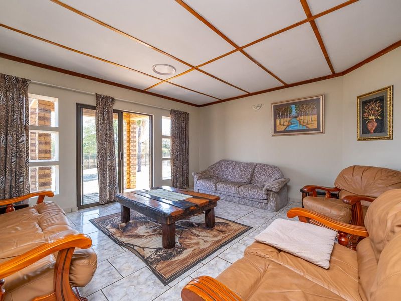 A living room featuring tiled flooring, a grid ceiling, and a sliding glass door providing access to the outdoor area.
