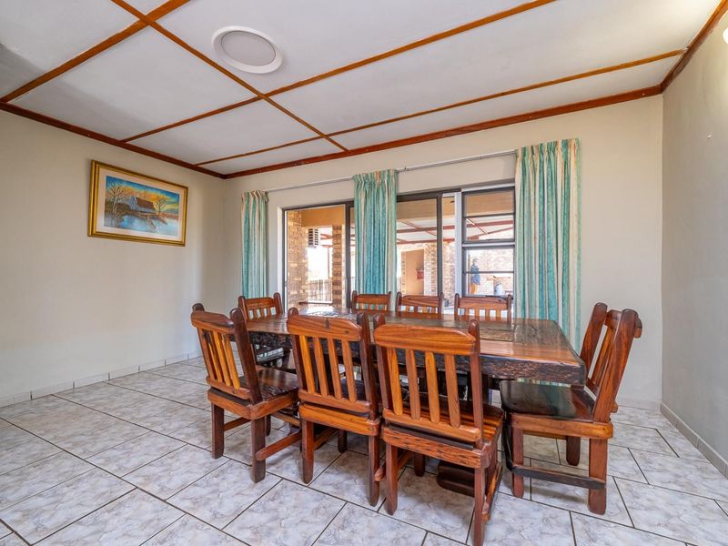 A dining room featuring tiled flooring, exposed ceiling beams, and sliding glass doors that provide access to an outdoor patio area.