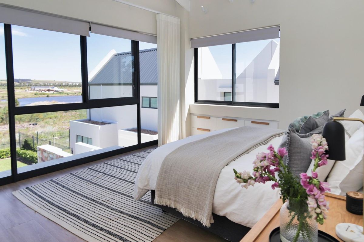 A bright, modern bedroom featuring large floor-to-ceiling windows with scenic views, built-in cabinetry, and high-quality finishes.