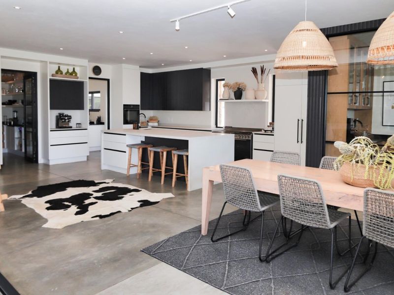 Modern open-plan living and kitchen area featuring polished concrete floors, a central kitchen island, and contemporary cabinetry with integrated appliances.