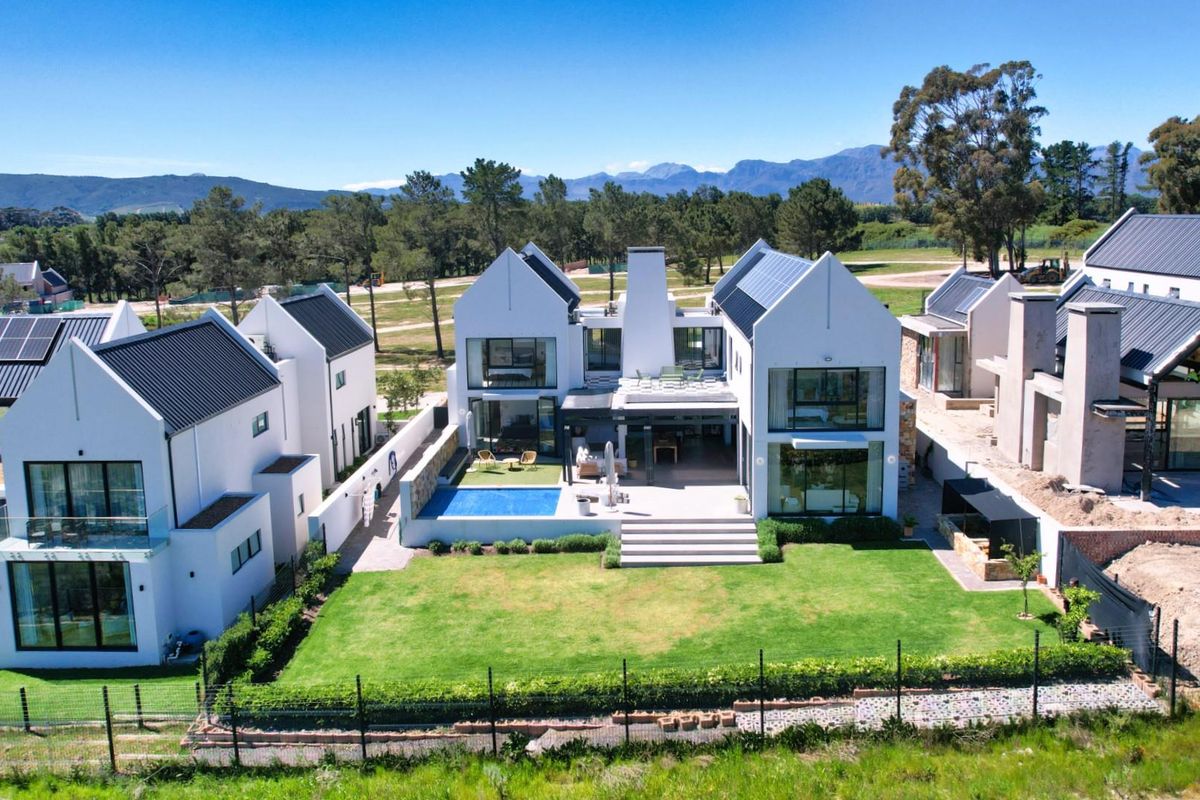 Aerial view of a modern residential property featuring a swimming pool, landscaped garden, and contemporary architectural design with solar panels.