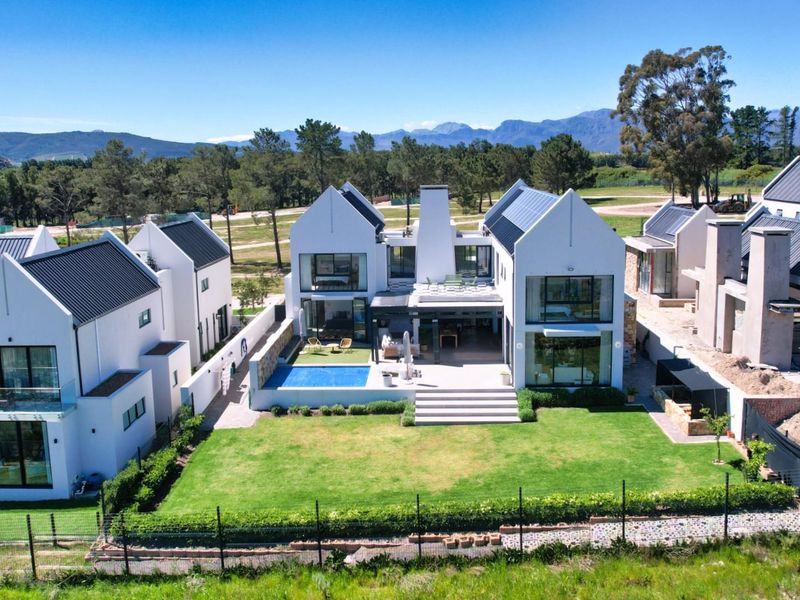 Aerial view of a modern residential property featuring a swimming pool, landscaped garden, and contemporary architectural design with solar panels.
