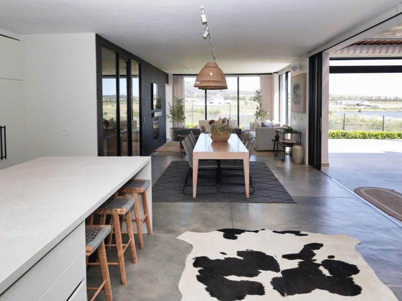 Spacious open-plan living area featuring a modern kitchen island, polished concrete floors, and seamless indoor-outdoor flow through large sliding glass doors.