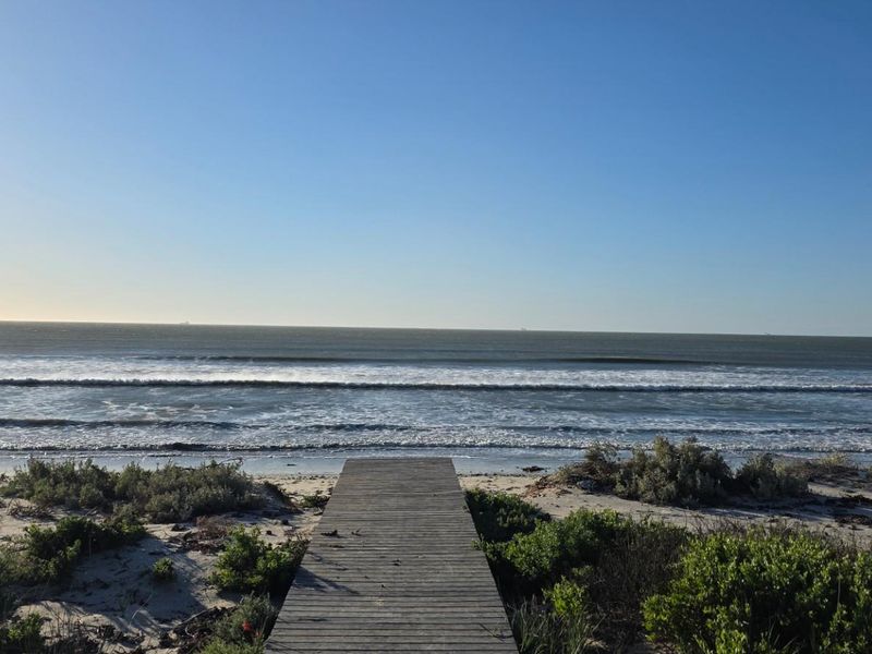 A scenic view of the ocean featuring a wooden boardwalk leading directly onto the sandy beach.