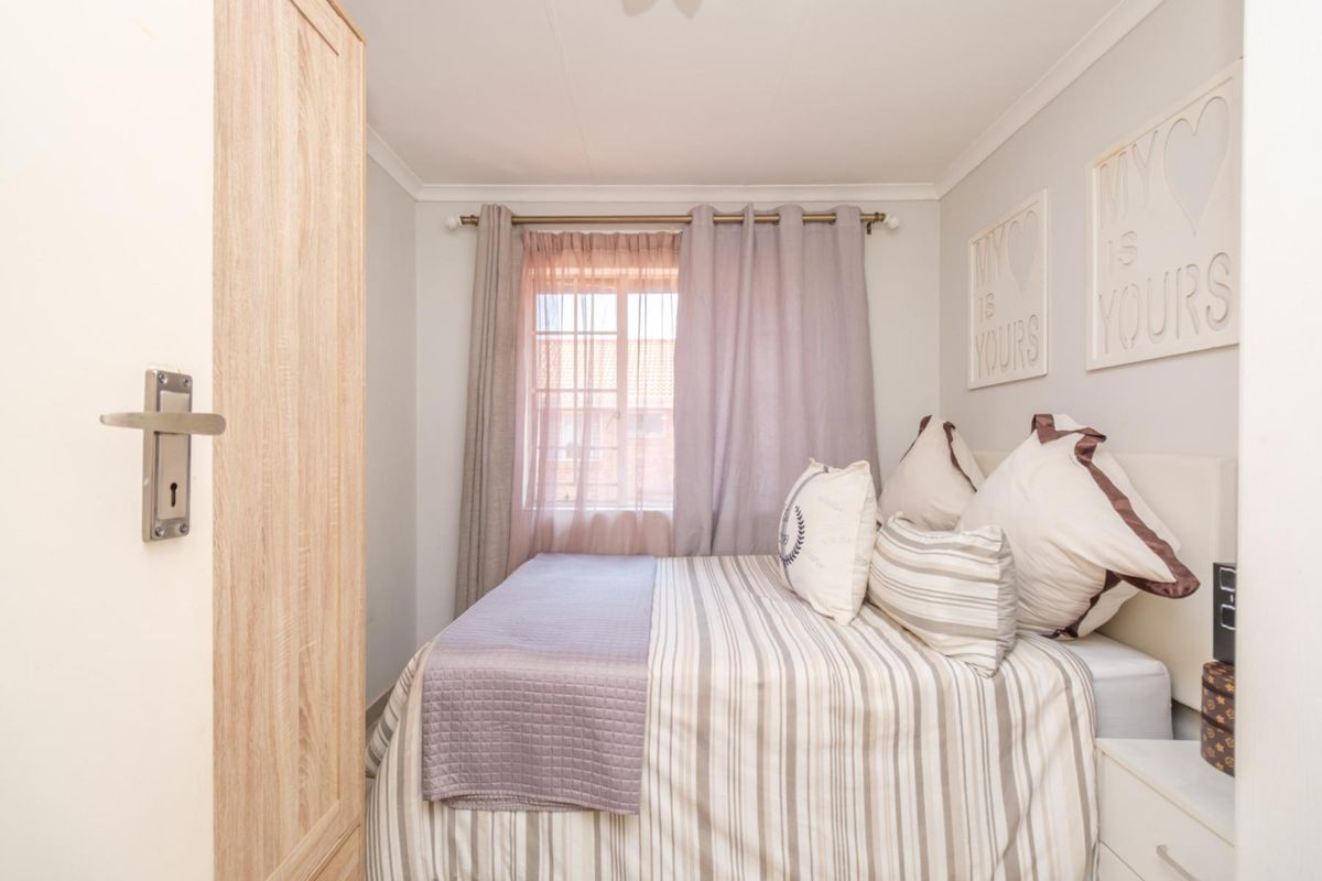 A cozy bedroom featuring neutral wall tones, coving, and a built-in cupboard, providing a functional and well-maintained living space.