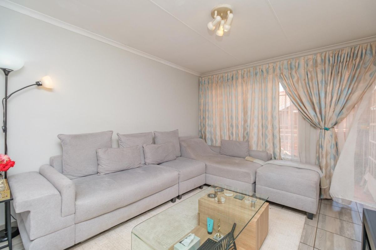 A comfortable living room featuring tiled flooring and natural light through large window curtains.