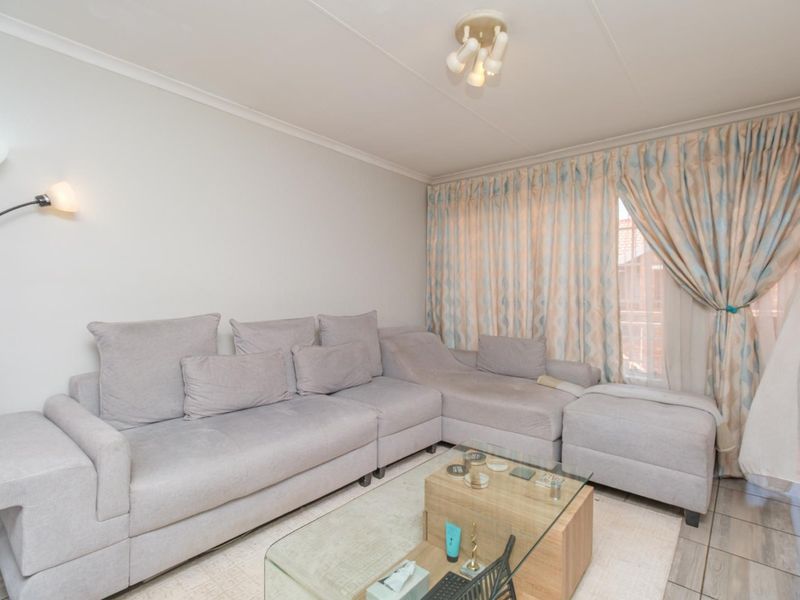 A comfortable living room featuring tiled flooring and natural light through large window curtains.