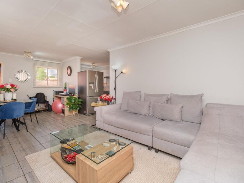 An open-plan living and dining area featuring tiled flooring, neutral walls, and natural light, creating a functional and connected living space.