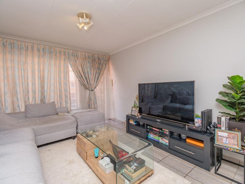 A comfortable living room featuring tiled flooring and neutral wall finishes, providing a functional space for relaxation and entertainment.