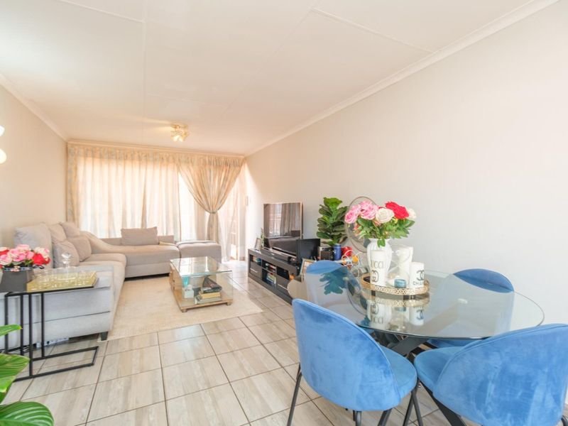 Open-plan living and dining area featuring neutral tiled flooring and a sliding glass door providing natural light.