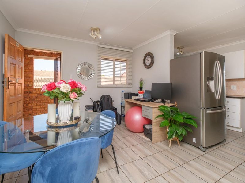 Open plan living and kitchen area featuring tiled flooring, neutral walls, and functional cabinetry, providing a versatile space for dining and daily activities.