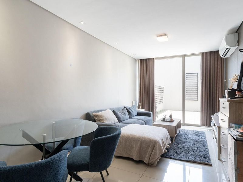 Modern open-plan living area featuring tiled floors, recessed lighting, and a sliding glass door providing access to the balcony.