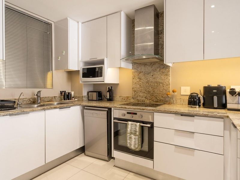 Modern kitchen featuring white cabinetry, granite countertops, stainless steel appliances, and integrated dishwasher, offering a clean and functional cooking space.