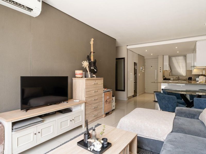 Modern open-plan living area featuring tiled floors, recessed lighting, and a sleek kitchen with stone countertops and integrated cabinetry.