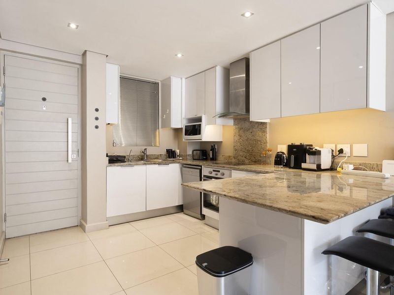Modern kitchen featuring sleek white cabinetry, granite countertops, integrated appliances, and recessed lighting, creating a clean and functional culinary space.