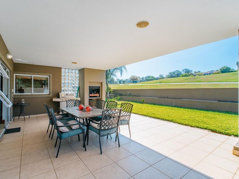 Covered patio featuring tiled flooring, a built-in braai, and a glass block wall, offering direct access to the garden and scenic views.
