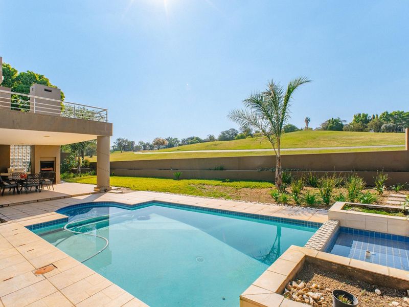 Outdoor pool area featuring a tiled patio, built-in braai, and a balcony overlooking a landscaped garden and golf course view.