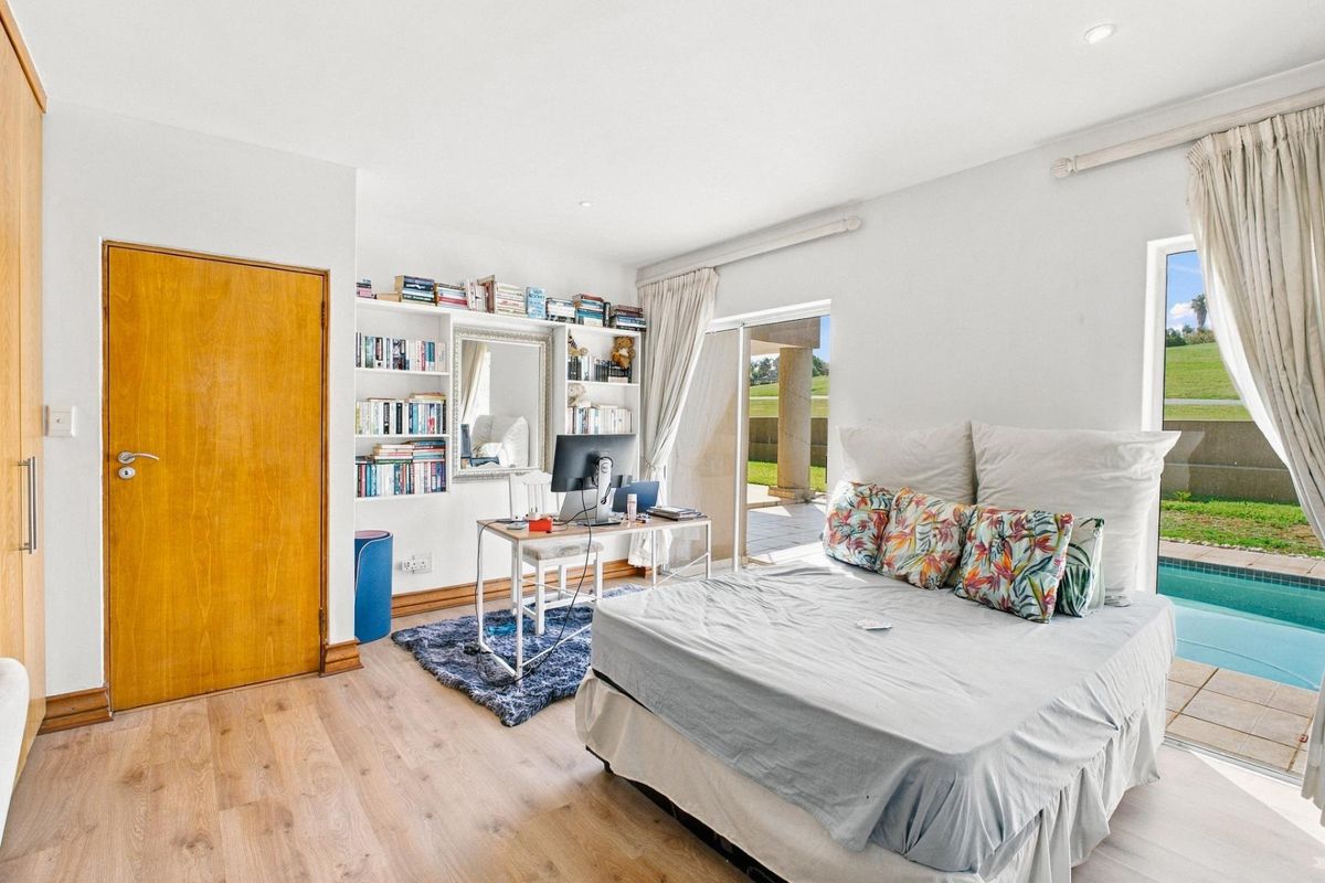 Bright bedroom featuring laminate flooring, built-in shelving, and a sliding glass door providing direct access to the patio and pool area.