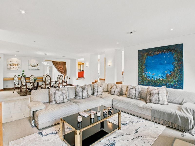Spacious open-plan living and dining area featuring neutral tones, recessed lighting, and a seamless transition between tiled and carpeted flooring zones.