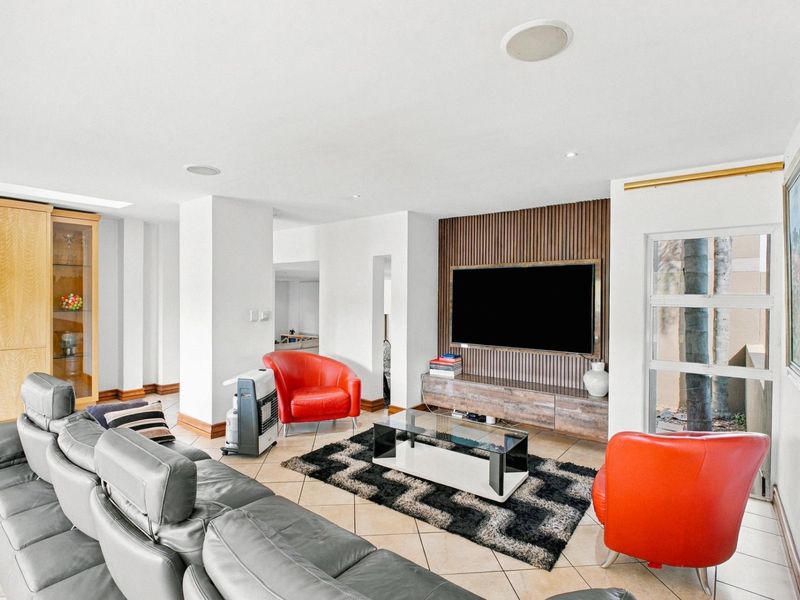 Spacious living room featuring a modern slatted wood feature wall, built-in cabinetry, tiled flooring, and recessed ceiling lighting.