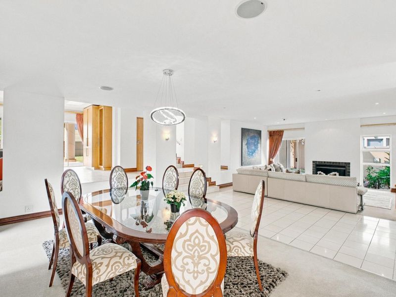 Spacious open-plan living and dining area featuring a built-in fireplace, neutral tiled and carpeted flooring, and recessed lighting throughout.