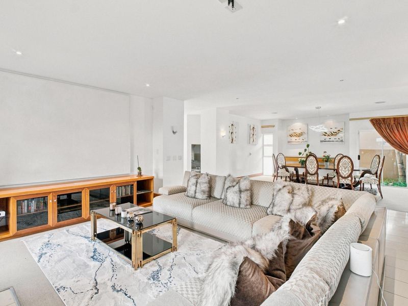 Spacious open-plan living and dining area featuring neutral tones, recessed lighting, and a seamless transition between carpeted and tiled flooring zones.