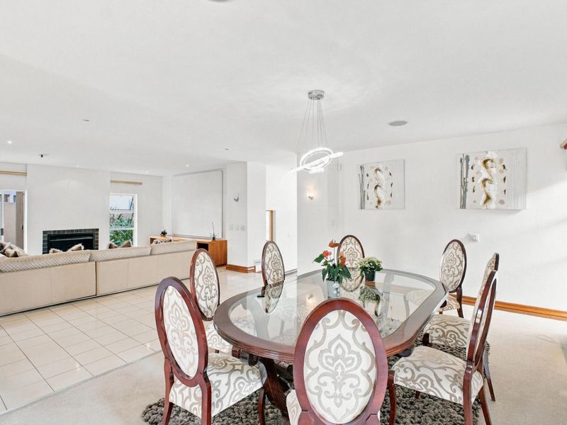 Spacious open-plan living and dining area featuring tiled and carpeted flooring, a built-in fireplace, and modern pendant lighting.