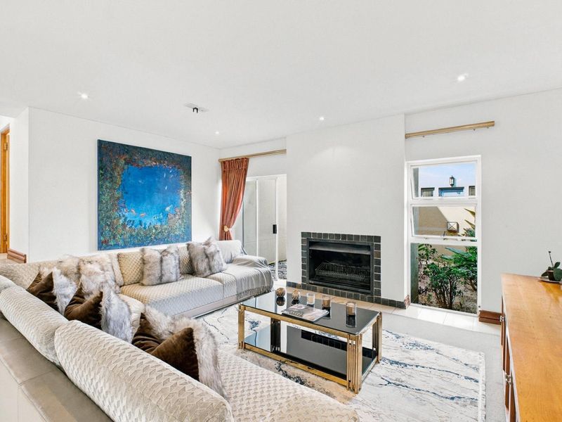 A bright living room featuring a fireplace with a tiled surround, recessed lighting, and access to an outdoor area through a sliding glass door.