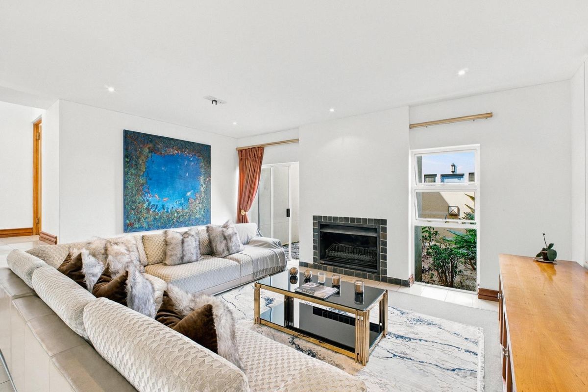A bright living room featuring a fireplace with a tiled surround, recessed lighting, and access to an outdoor area through a sliding glass door.