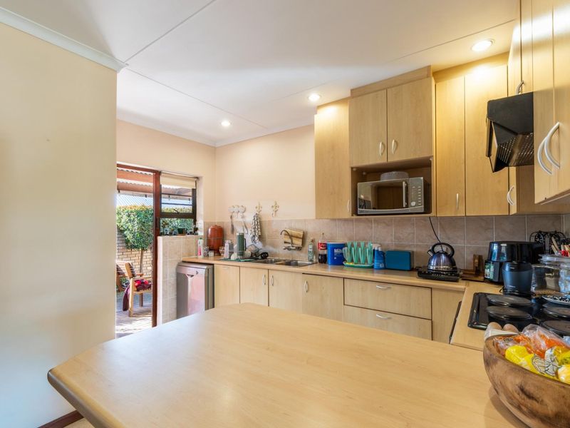 Functional kitchen featuring light wood-look cabinetry, laminate countertops, built-in appliances, and direct access to an outdoor patio area.