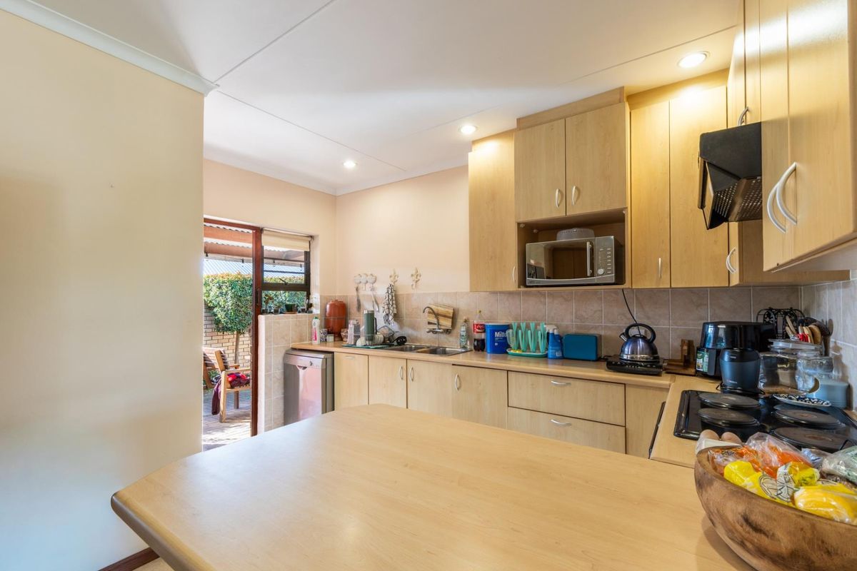 Functional kitchen featuring light wood-look cabinetry, laminate countertops, built-in appliances, and direct access to an outdoor patio area.