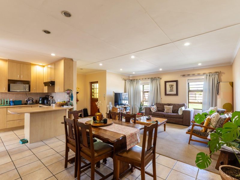 Open-plan living, dining, and kitchen area featuring light wood cabinetry, tiled flooring, and recessed lighting, creating a functional and connected family space.