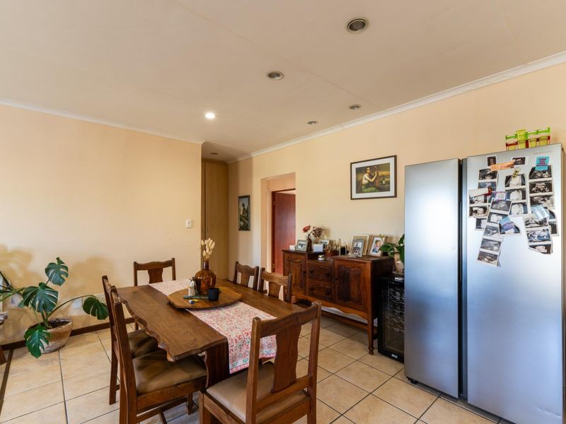 A dining area featuring tiled flooring and recessed downlighting, providing a functional space for meals with access to adjacent rooms.