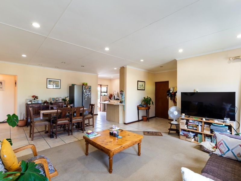 Spacious open-plan living and dining area featuring a mix of tiled and carpeted flooring, recessed lighting, and a breakfast bar connecting to the kitchen.
