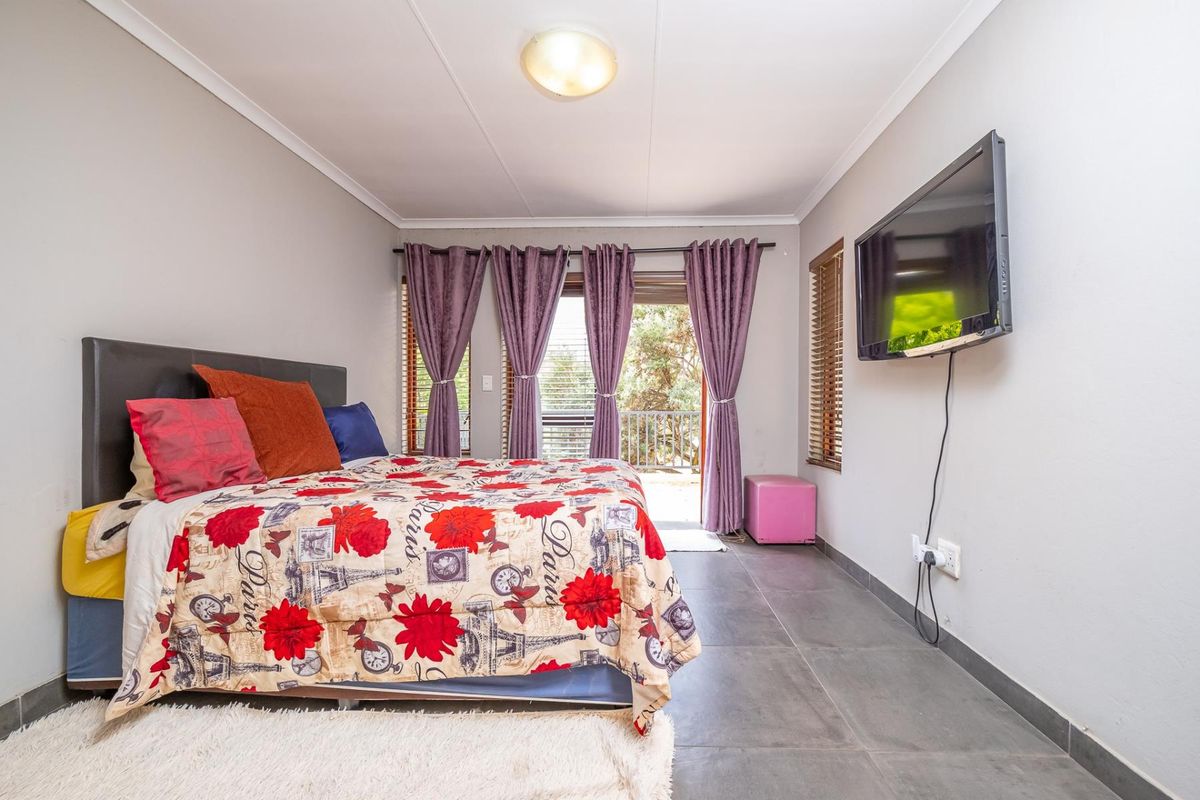 A bedroom featuring tiled flooring, a wall-mounted television, and a sliding glass door providing access to an outdoor area.