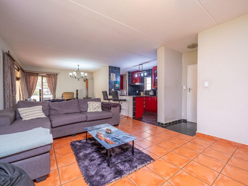 Open plan living area featuring tiled floors and a kitchen with red cabinetry and a breakfast counter.