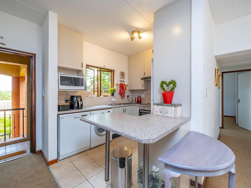 Compact kitchen featuring built-in cabinetry, laminate countertops, integrated oven, extractor fan, and a functional breakfast nook with tiled flooring.