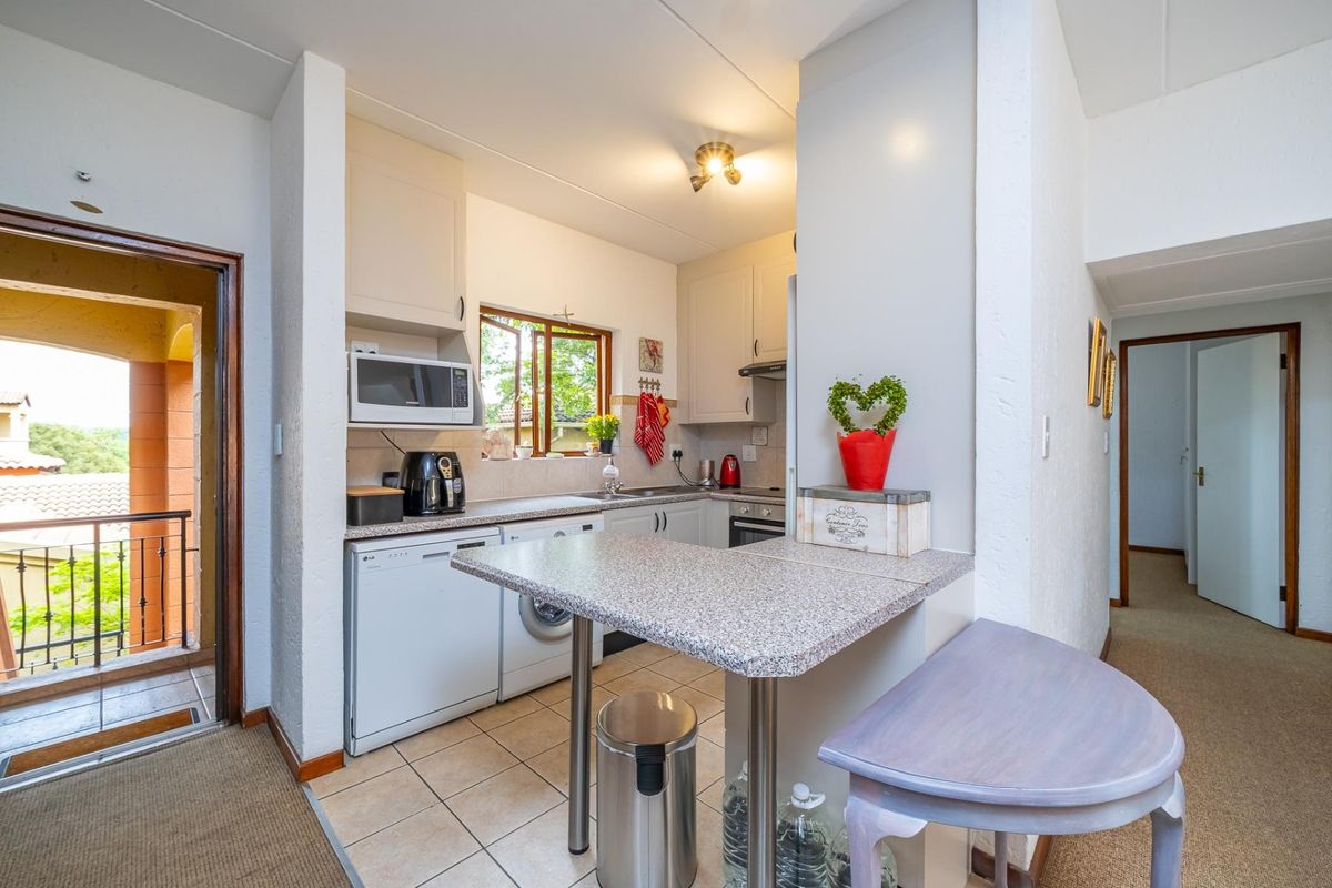 Compact kitchen featuring built-in cabinetry, laminate countertops, integrated oven, extractor fan, and a functional breakfast nook with tiled flooring.