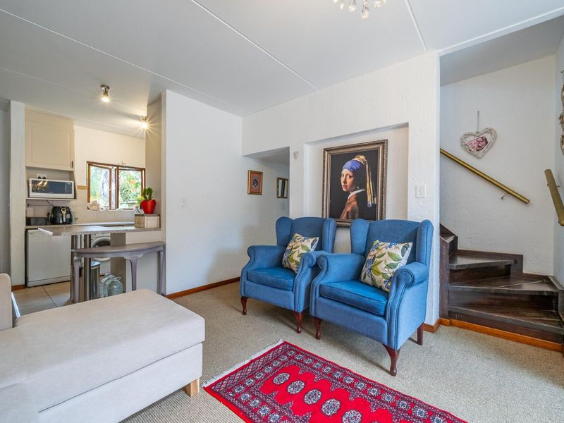 Open-plan living area featuring a compact kitchen with built-in cabinetry and a staircase leading to the upper level.