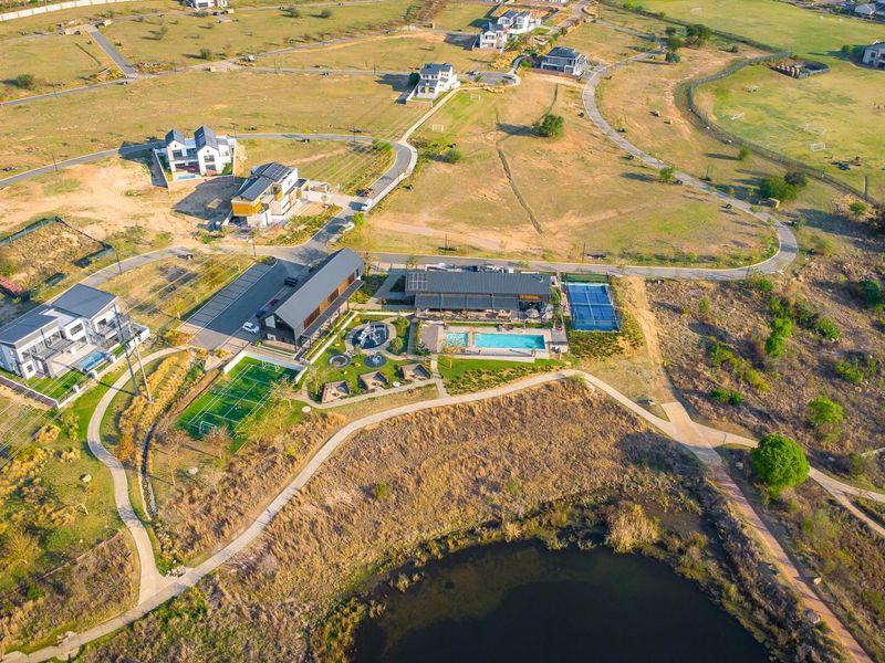 Aerial view of a residential estate featuring a swimming pool, tennis court, soccer field, and extensive landscaped communal areas.