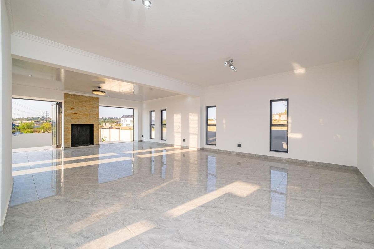 Spacious, light-filled living area featuring polished porcelain tiles, a stone-clad fireplace, and large stacking doors opening to the exterior.