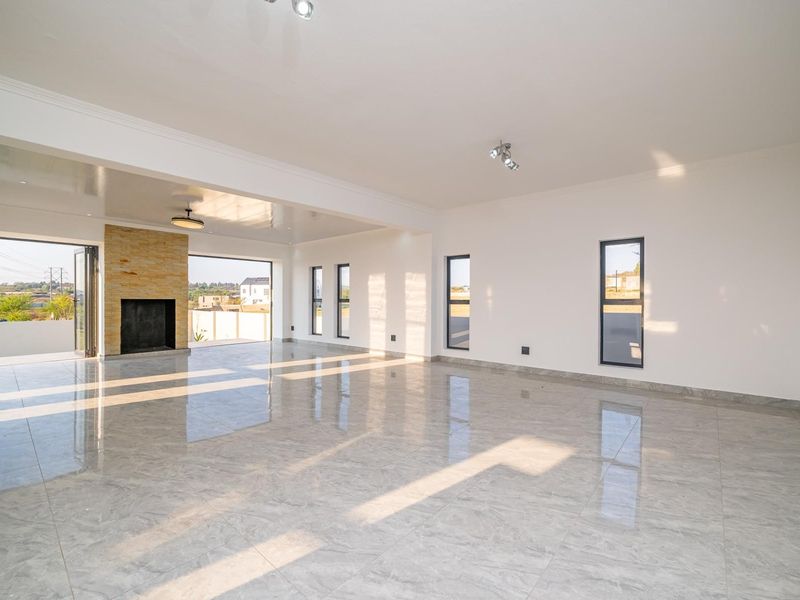 Spacious, light-filled living area featuring polished porcelain tiles, a stone-clad fireplace, and large stacking doors opening to the exterior.